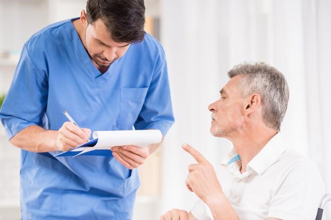Male student physician writes notes as teacher advises.